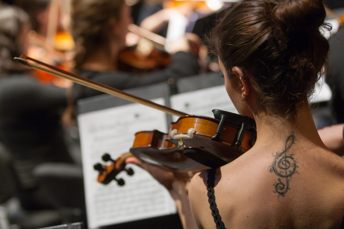 en la imagen, tomada desde detrás, la nuca de una violinista que toca su partitura